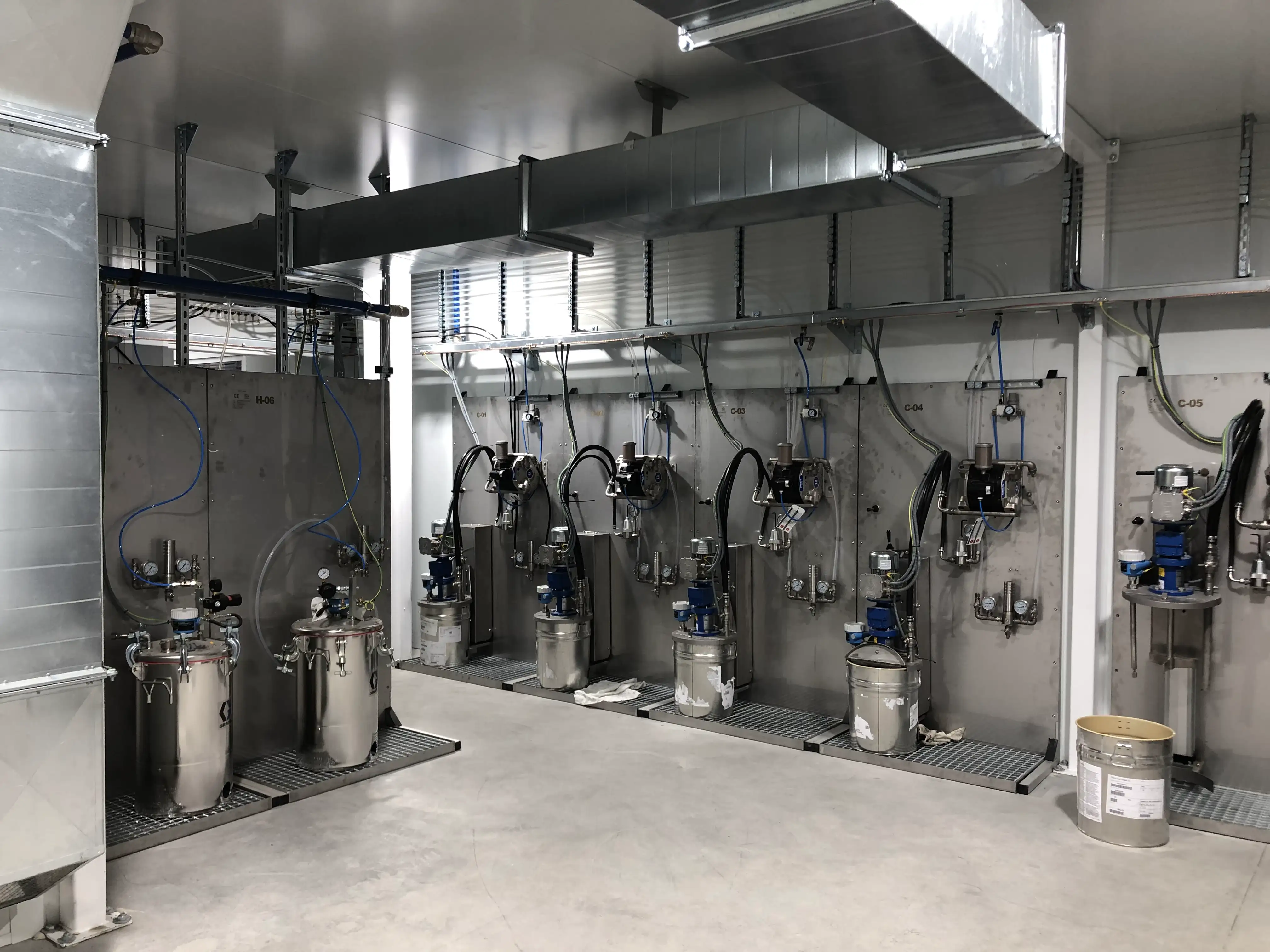 Vista de una sala de mezclas de pintura industrial, equipada con tanques de almacenamiento, tuberías de circulación y agitadores automáticos, diseñada para garantizar precisión en la mezcla y consistencia en el suministro de pintura.